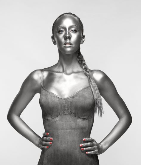 Dr Emily Andre stands with hands on hips covered head to toe in metallic paint 
